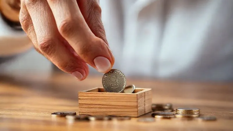A photorealistic image of a person's hand carefully selecting a single, valuable coin from a small, open wooden box, surrounded by other less valuable items. The lighting is soft and contemplative, highlighting the delicate decision-making process. Sharp focus on the coin being chosen, with a shallow depth of field. Shot on a high-end DSLR, 8K, conveying careful consideration and a measured approach.