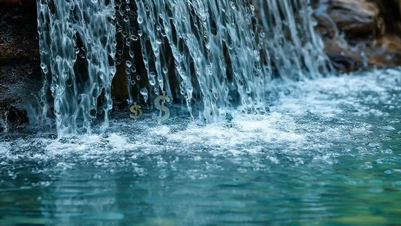 A photorealistic image of a cascading waterfall flowing into a calm pool, with various financial symbols (dollar signs, euro symbols, yen symbols) subtly embedded in the water, representing steady income streams. Professional photography, 8K, cinematic lighting, sharp focus on the flowing water and symbols, depth of field blurring the background, shot on a high-end DSLR.