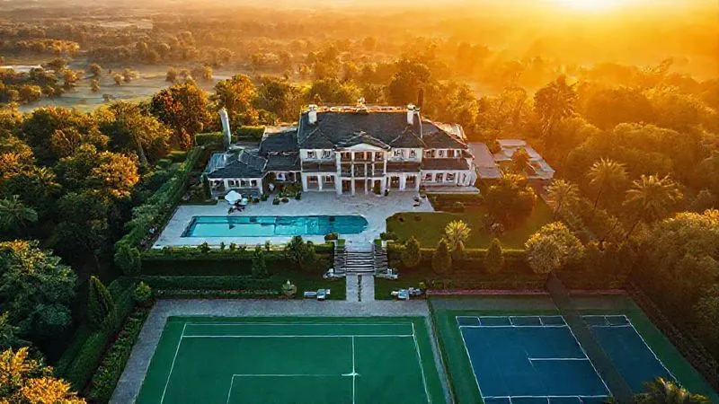 A photorealistic overhead drone shot of a sprawling luxury estate with a beautifully manicured garden, swimming pool, and tennis court, bathed in golden hour cinematic lighting. The image conveys a sense of peaceful grandeur and an aspirational lifestyle, 8K, sharp focus, depth of field, shot on a high-end DSLR.