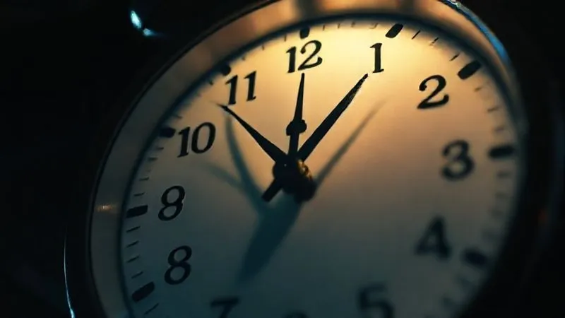 A photorealistic image of a clock face illuminated by dramatic, cinematic lighting, with the hands nearing midnight, emphasizing urgency and the final hours of a crowdfunding campaign. Professional photography, 8K, sharp focus on the clock, depth of field blurring the background, shot on a high-end DSLR.