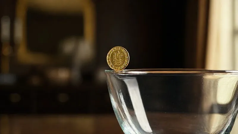photorealistic, professional photography, 8K, cinematic lighting, sharp focus, depth of field, shot on a high-end DSLR. A single gold coin, precariously balanced on the edge of a large, empty glass vase, symbolizing the fragility of unsecured wealth and the risk of dissipation. The background is a dimly lit, elegant study. The coin is in sharp focus, the vase and background are softly blurred.