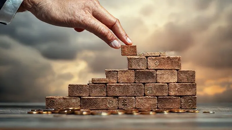 Photorealistic, professional photography, 8K, cinematic lighting, sharp focus, depth of field, shot on a high-end DSLR. A professional's hand placing a small, meticulously crafted brick onto a growing, solid financial wall made of various currency symbols and coins, against a blurred background of stormy clouds, symbolizing building financial resilience against future professional liability risks. The focus is on the secure, growing wall.